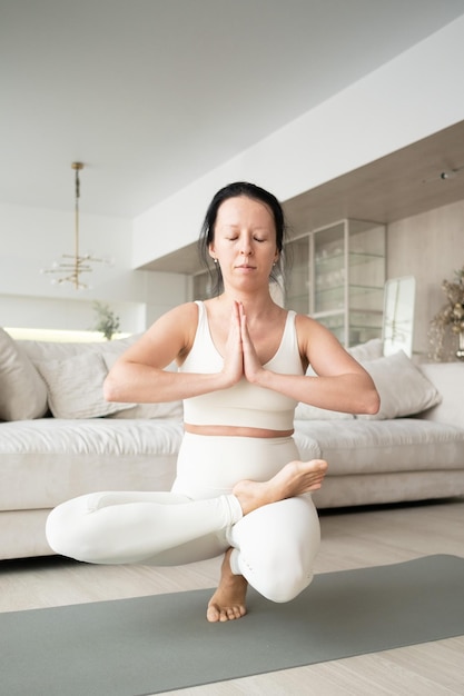 Schwangere Frau beim vorgeburtlichen Yoga zu Hause im Wohnzimmer Fitness für Schwangere