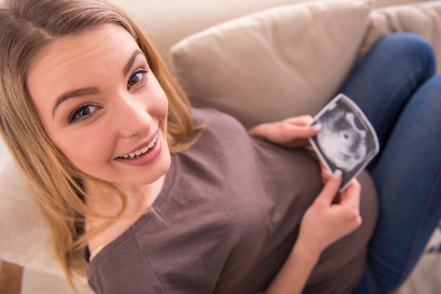 Schwangere Frau betrachtet Ultraschallscan des Babys.