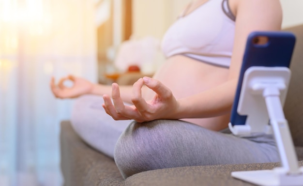 Schwangere Frau bleibt allein zu Hause. Schwangerschafts-Online-Lernen für Yoga und Training. Gesund und wohlfühlen.