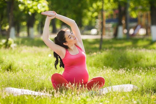 Schwangere Frau der Junge, die Yogaübungen tut.