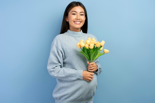 Schwangere Frau des jungen schönen Brunette, die Baby erwartet, das Blumenstrauß hält