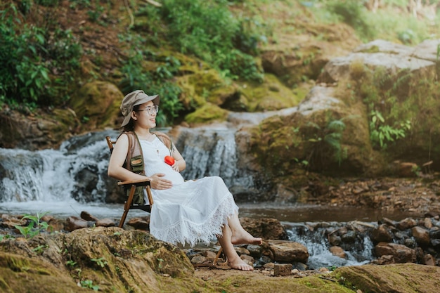 Schwangere Frau, die am Wasserfall sitzt