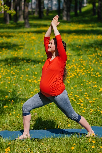 Schwangere Frau, die Asana im Freien tut