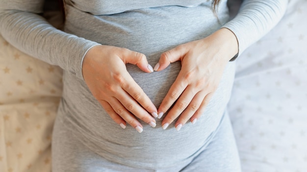 Schwangere frau, die auf dem bett liegt und ihren bauch hält