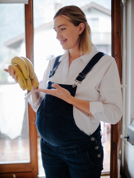 Schwangere Frau, die Bananen betrachtet