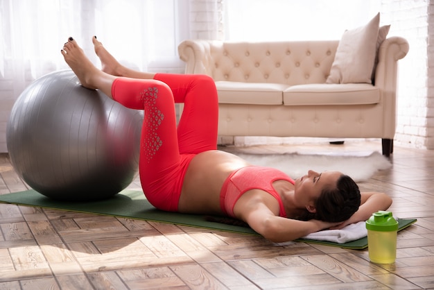 Schwangere Frau, die das Trainieren auf Yoga-Teppich tut.