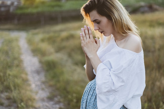 Foto schwangere frau, die draußen bei sonnenuntergang betet. konzept für glauben, spiritualität und religion. frieden, hoffnung