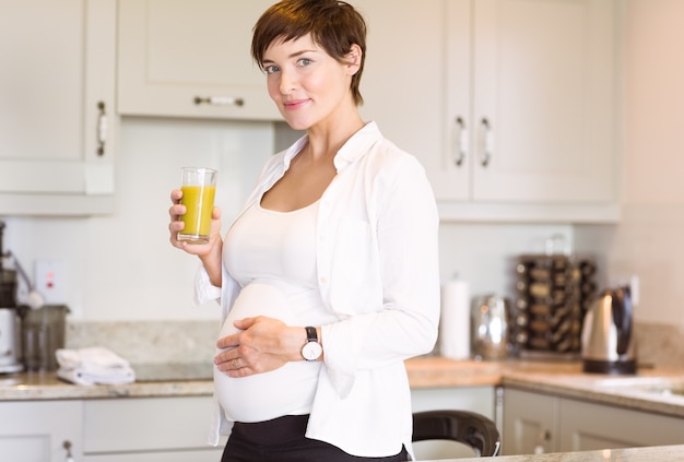 Schwangere Frau, die ein Glas Orangensaft isst