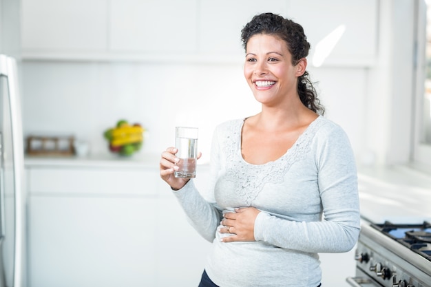 Schwangere Frau, die ein Glas Wasser hält