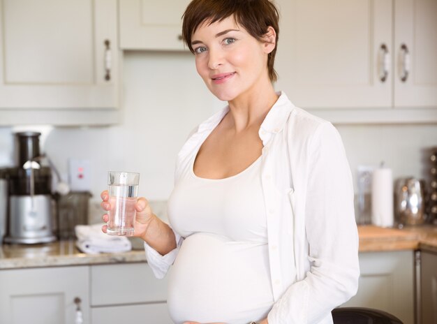 Schwangere Frau, die ein Glas Wasser isst