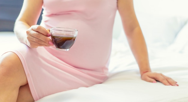Schwangere Frau, die eine Tasse Kaffee hält