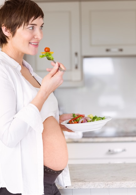 Schwangere Frau, die einen Salat isst