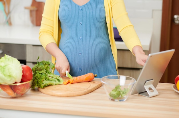 Schwangere Frau, die gesundes Essen aus frischen Zutaten zubereitet