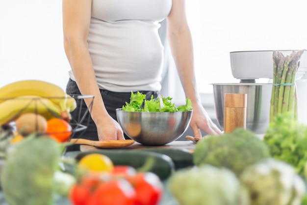 Schwangere Frau, die gesundes Lebensmittel kocht