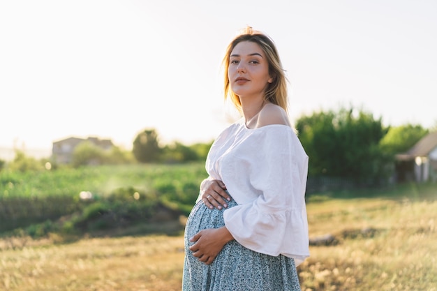 Schwangere Frau, die im Feld steht