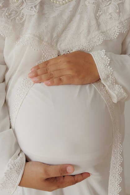 Schwangere Frau, die mit beiden Händen den Bauch hält