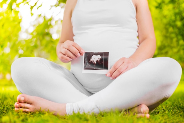 Schwangere Frau, die Ultraschallbild hält