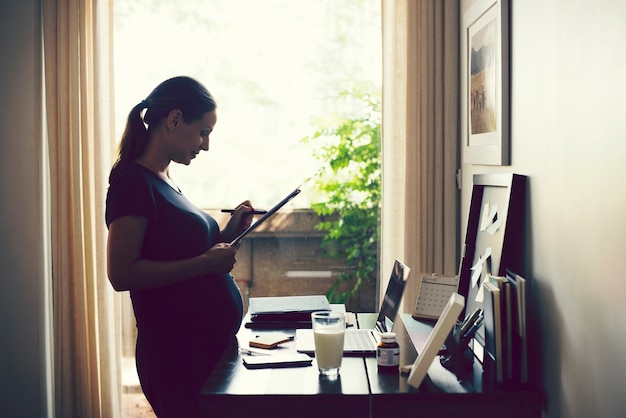 Schwangere Frau, die vom Haus arbeitet