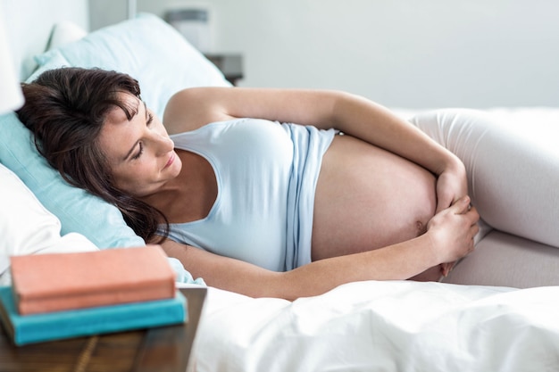 Schwangere Frau, die zu Hause auf ihrem Bett stillsteht