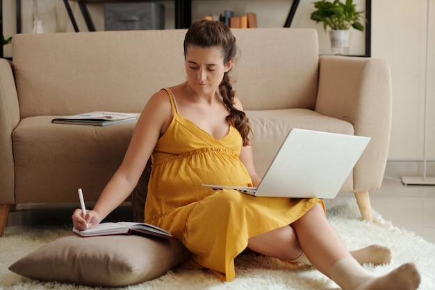 Schwangere Frau, die zu Hause studiert