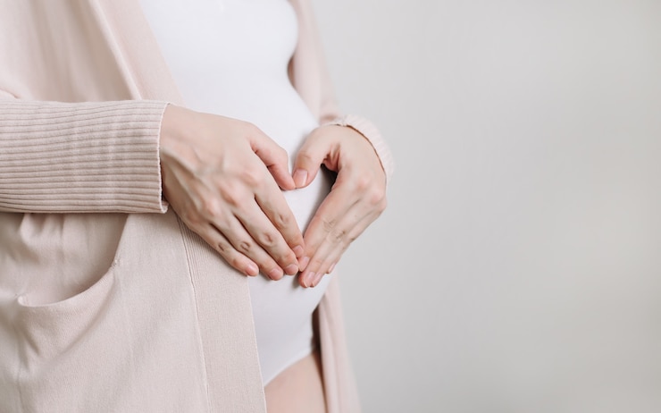 Foto schwangere frau hält die hände auf dem bauch auf einem weißen hintergrund schwangerschaftsvorbereitungs- und erwartungskonzept