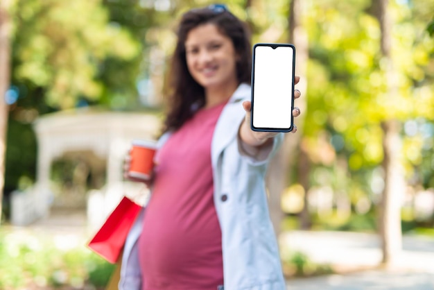 Foto schwangere frau hält ein handy mit weißem rücken