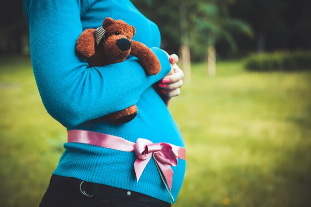 Schwangere Frau hält einen Teddybär