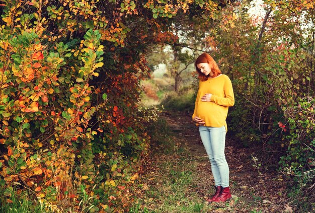 Schwangere Frau im Herbst Foto einer gesunden Schwangerschaft Werdende Mutter geht im Herbstpark