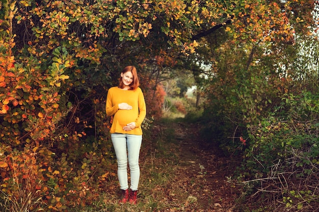 Schwangere Frau im Herbst Foto einer gesunden Schwangerschaft Werdende Mutter geht im Herbstpark