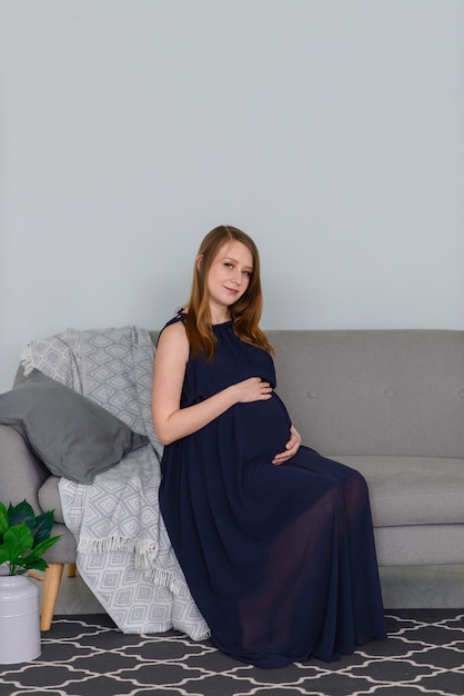 Schwangere Frau im Kleid umarmt ihren dicken Bauch