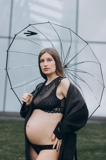 schwangere Frau in einem Regenmantel im Park