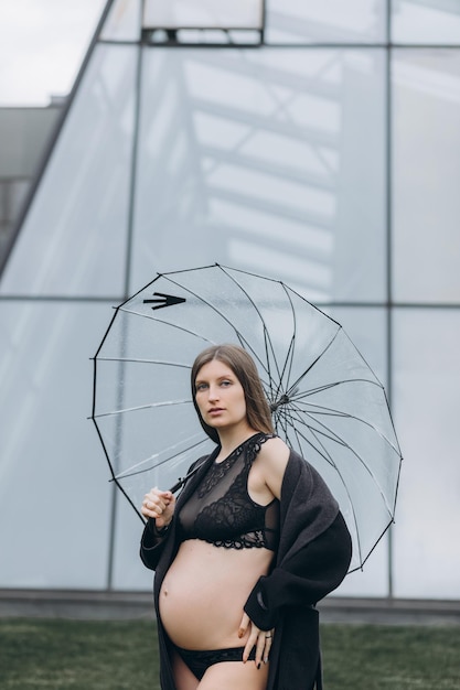 schwangere Frau in einem Regenmantel im Park