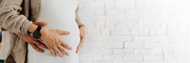 Schwangere Frau in einem weißen Kleid mit ihrem Mann in einem Wohnzimmer