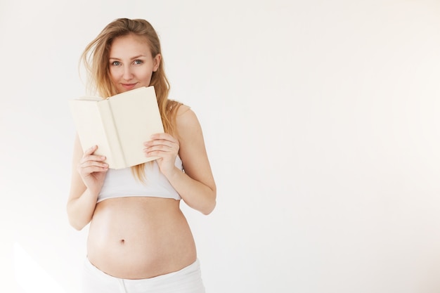 Schwangere Frau liest ein Buch über gesunde Ernährung und Stillen oder entspannt sich einfach und nimmt sich Zeit für einen Mutterschaftsurlaub.