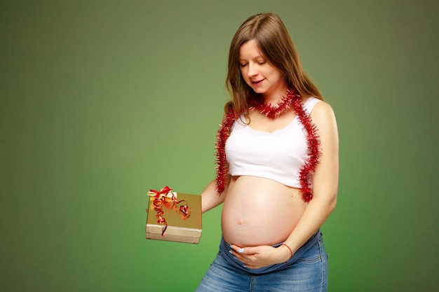 Schwangere Frau mit einem Geschenk, das an Heiligabend ein Geschenk für ein Baby an einem neuen Jahr bekommt