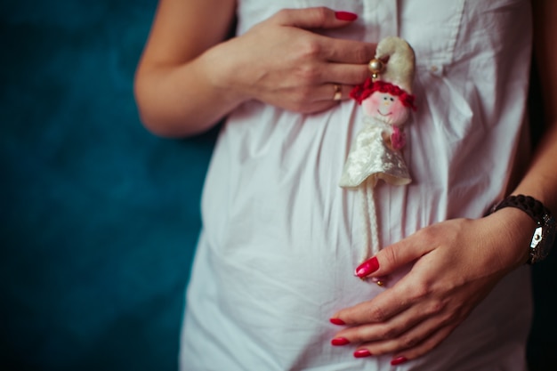 Schwangere Frau mit einer Puppe in der Hand