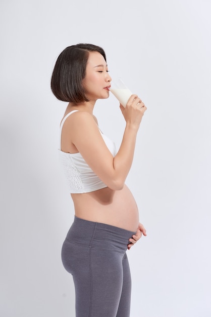 Schwangere Frau mit Glas Milch in der Hand gut gesund, isoliert auf weißem Hintergrund.