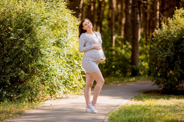 schwangere Frau mit Kleid, das in der Natur aufwirft