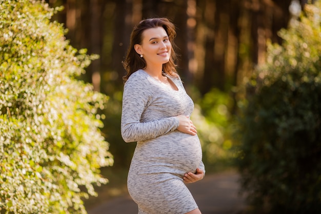 schwangere Frau mit Kleid, das in der Natur aufwirft