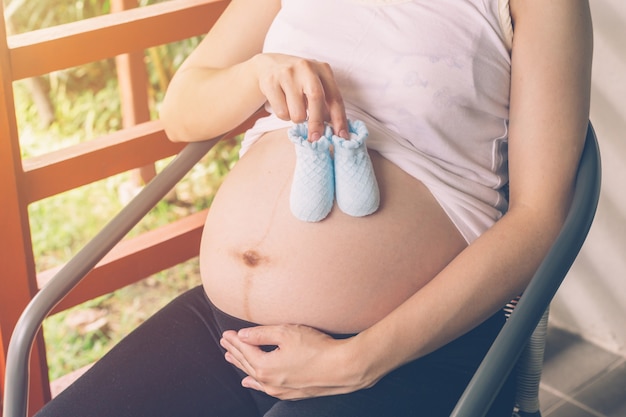 Schwangere Frau mit kleinen Baby-Schuhe auf ihren Bauch