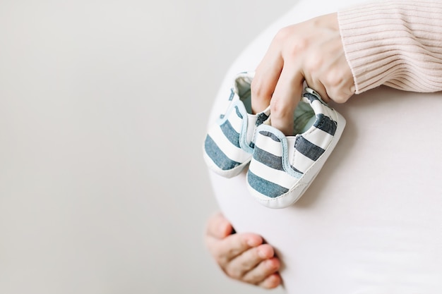 Schwangere Frau mit Schuhen für das Neugeborene