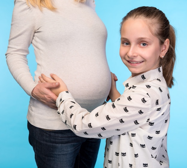 Schwangere Frau mit Tochter auf einer blauen Wand