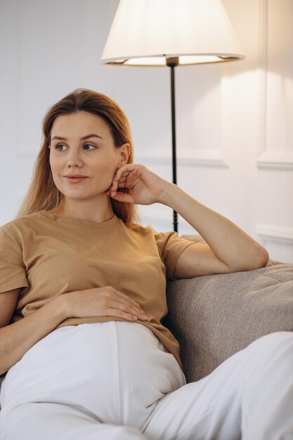 Schwangere Frau sitzt zu Hause auf dem Sofa