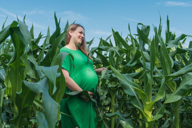 Schwangere Frau steht auf dem Maisfeld