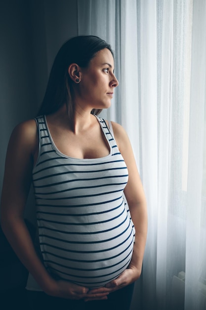 Foto schwangere frau steht zu hause am fenster