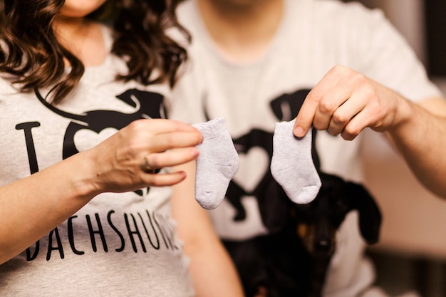 Schwangere Frau und ihr Mann halten kleine Socken für ihr zukünftiges Baby. Foto