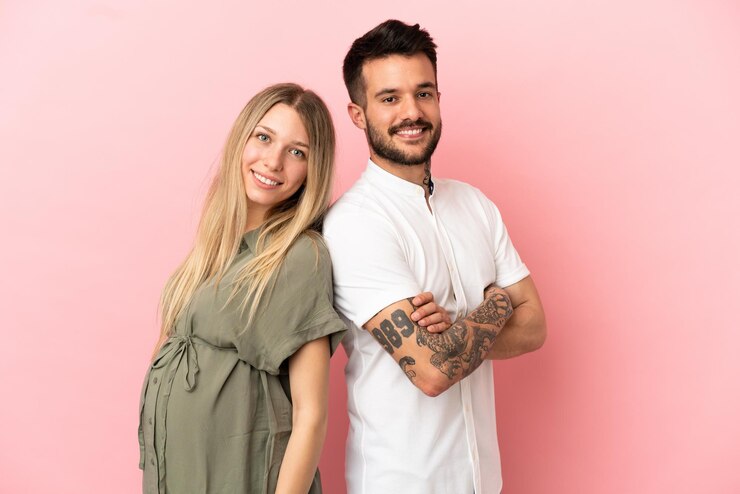 Foto schwangere frau und mann über isoliertem rosa hintergrund halten die arme verschränkt