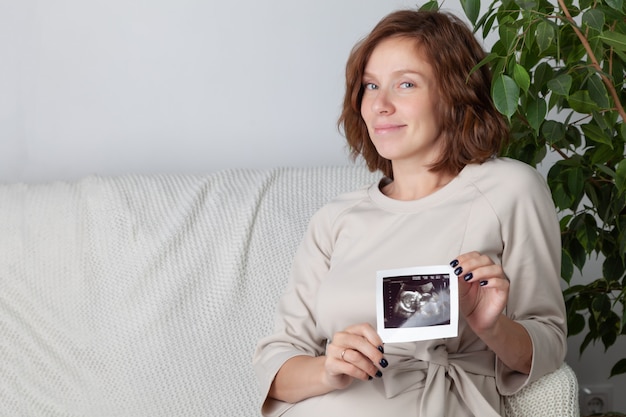 Schwangere Frau zeigt Bild des Ultraschallscans