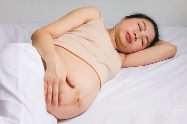 Foto schwangere frauen des asiaten legen auf das bett