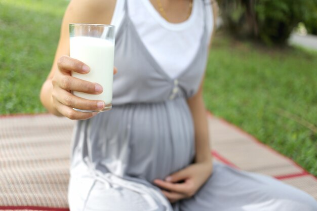 Schwangere Frauen haben ein Glas Milch in der Hand.